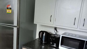 Een keuken met een roestvrijstalen koelkast, een magnetron en een koffiezetapparaat op het aanrecht.