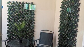 A small outdoor seating area with a round table and two chairs, surrounded by decorative foliage panels. - Midtown Midrise- Sapphire 200-The heart of Sacramento (Sacramento)