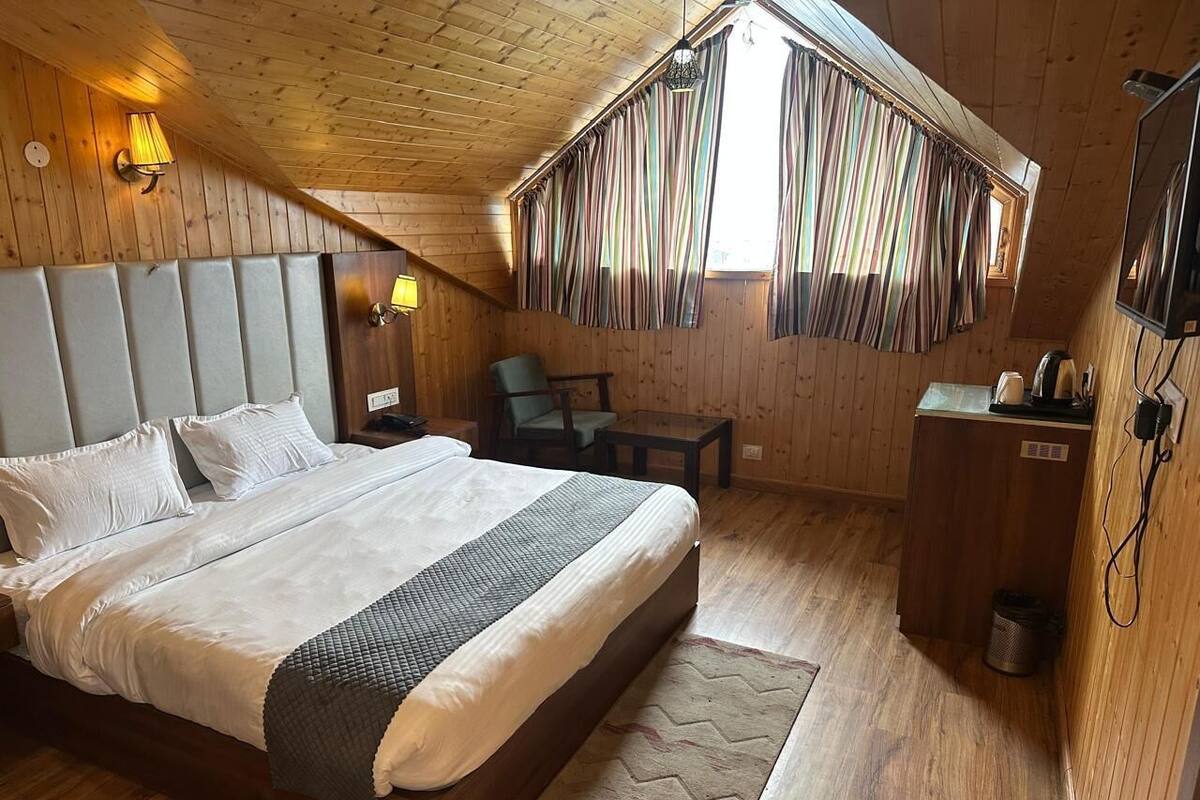 A bedroom with a large bed, a desk, a chair, and a small table.