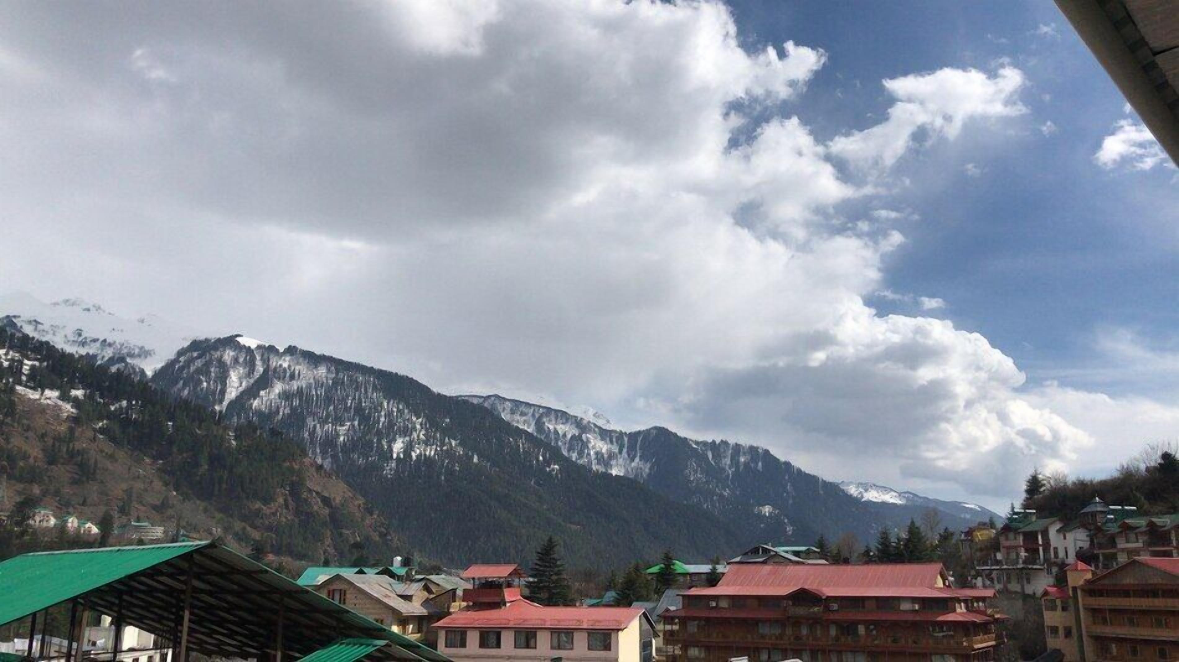 Un paysage montagneux avec des sommets enneigés et un village aux maisons traditionnelles.