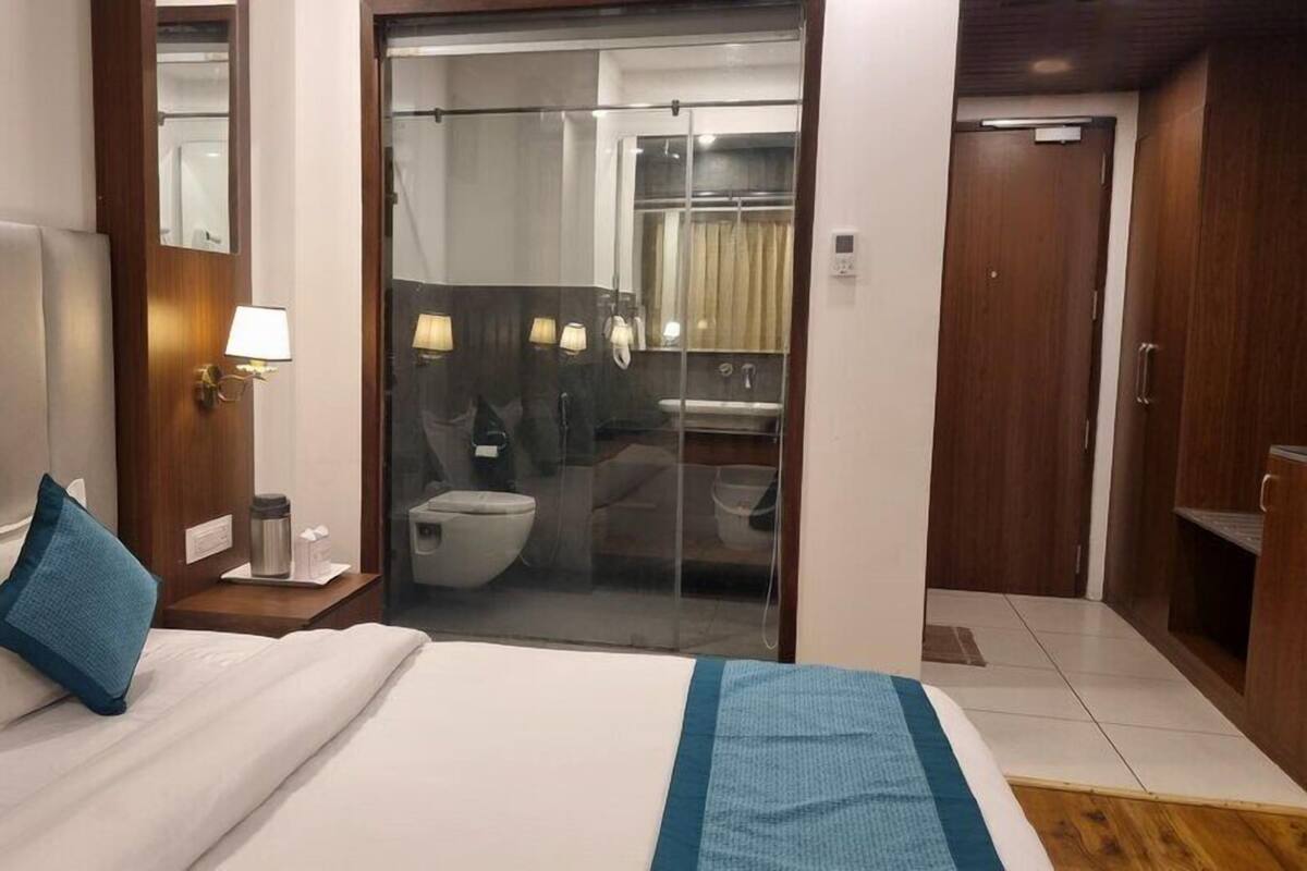 A hotel room with a bed, a bedside table with a lamp, a bathroom with a toilet and a shower, and a wardrobe.