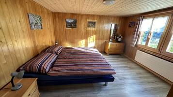 Ein Schlafzimmer mit Holzwänden, einem Bett, einem Schminktisch und Kunstwerken an den Wänden.