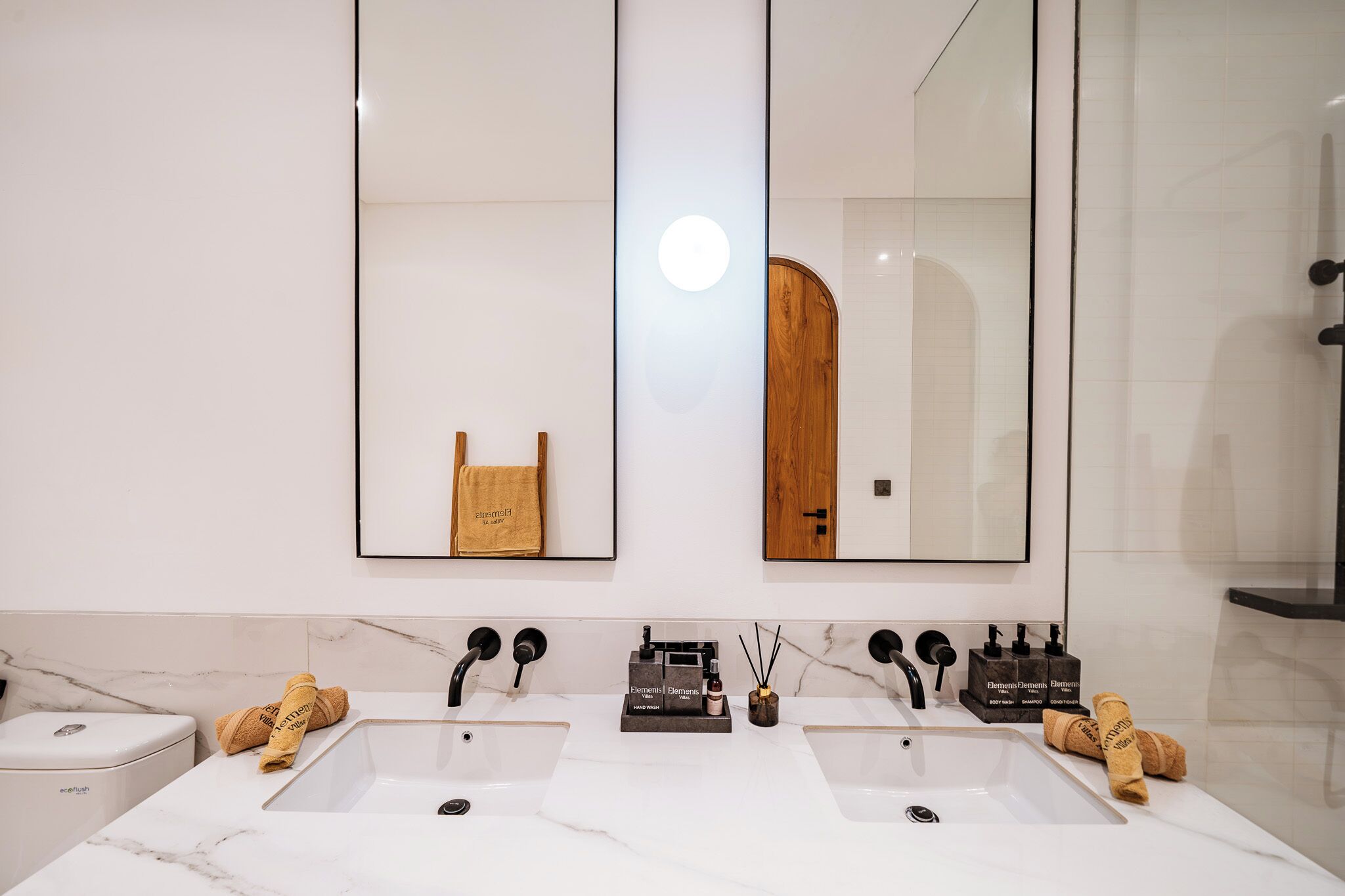 Un bagno moderno con due lavandini, uno specchio grande e un porta asciugamani.