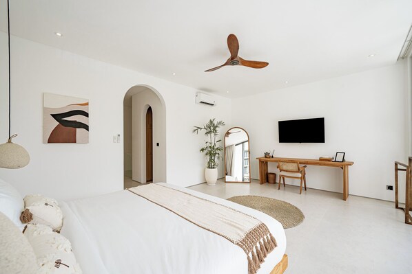 Une chambre à coucher moderne, équipée d’un lit, d’un bureau, d’une télévision et d’un ventilateur de plafond.