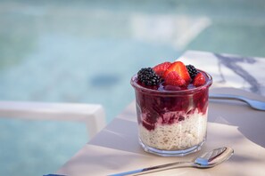 A dessert in a glass on a table with a spoon beside it.