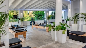 A modern indoor gym with exercise equipment, including a rowing machine and stationary bikes. - Villa K Hotel (Corfu)