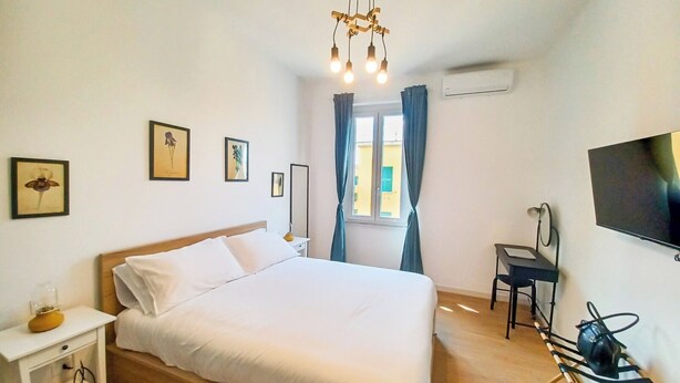 A hotel room with a bed, bedside table, TV, and a desk with a chair. - New Suite with modern living room in central area. (Roma)