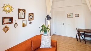 A living room with a sofa, a dining table, and a potted plant. - New Suite with modern living room in central area. (Roma)