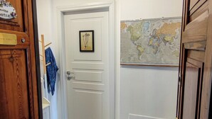 A hallway with a white door, a framed botanical illustration, and a world map on the wall. - New Suite with modern living room in central area. (Roma)