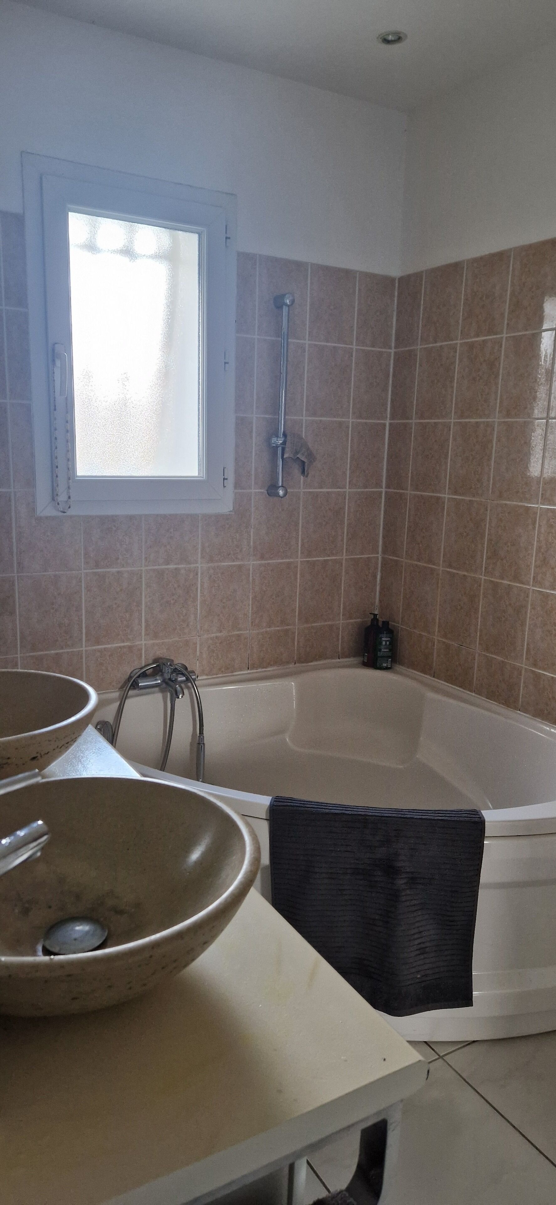 A bathroom with a bathtub, two sinks, a window, and tiled walls.