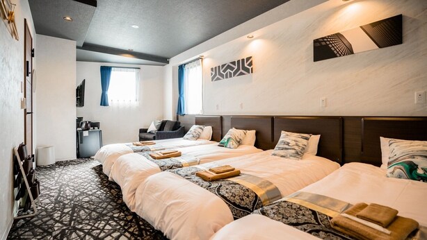 A hotel room with two beds, a sofa, a small table, and a TV.