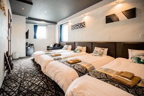 Une chambre d’hôtel avec deux lits, un canapé, une petite table et un téléviseur.