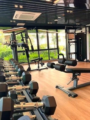 A gym with exercise equipment, large windows, and a view of greenery.