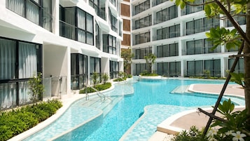 Ett modernt hotell med en swimmingpool, flera balkonger och ett välskött trädgårdsområde.