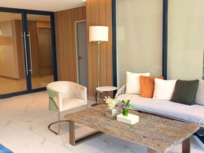 A modern living room with a sofa, armchair, and coffee table. - Laya Suites & Residences (Choeng Thale)