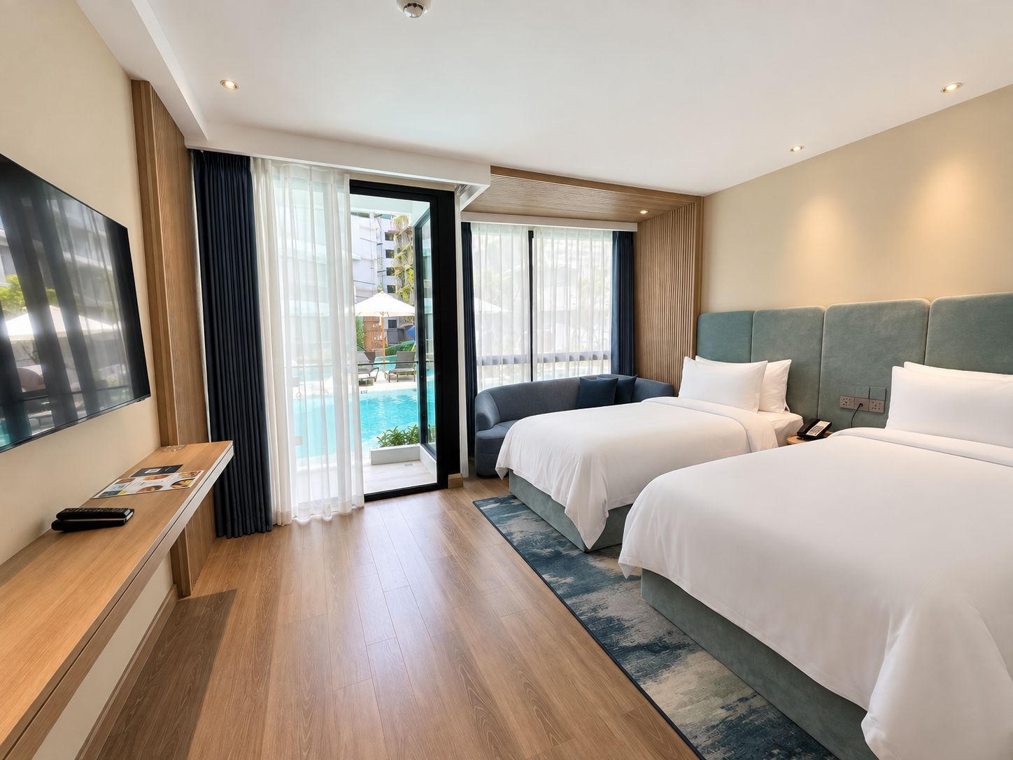 A hotel room with two beds, a TV, and a view of a swimming pool.