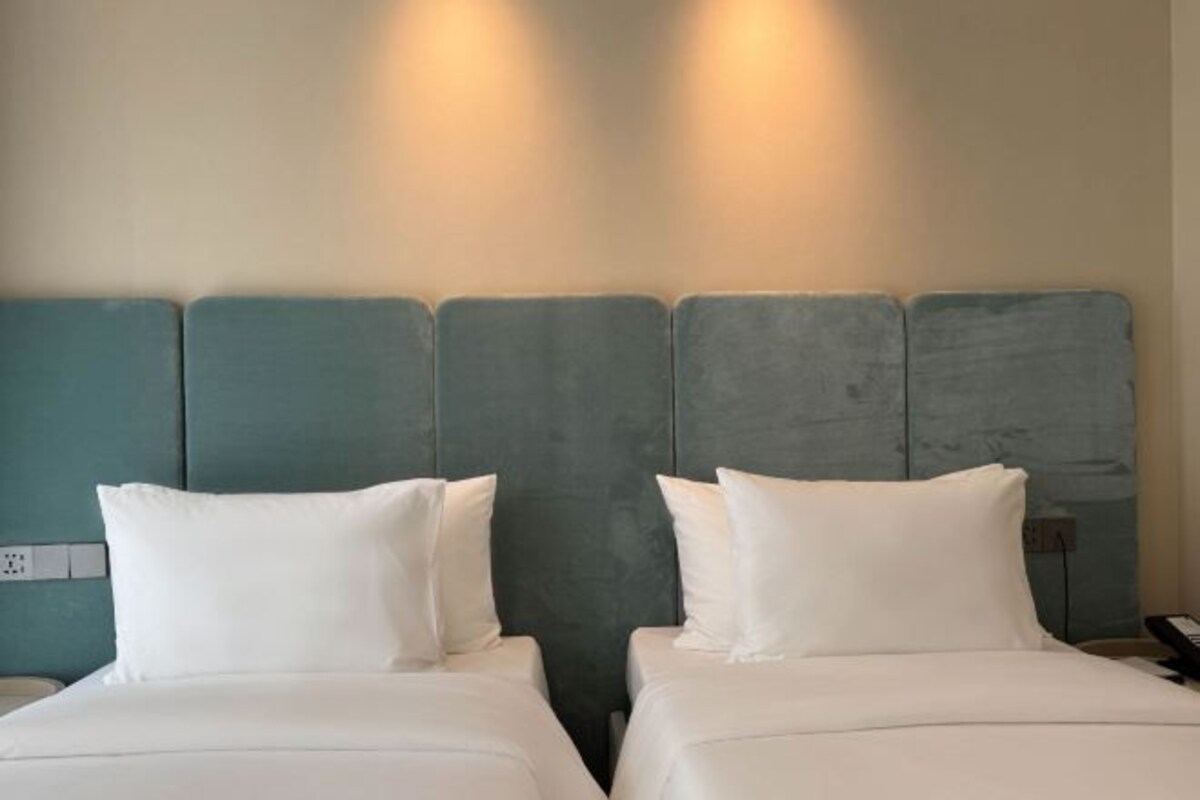 Ett hotellrum med två sängar, en sänggavel och ett vägguttag.