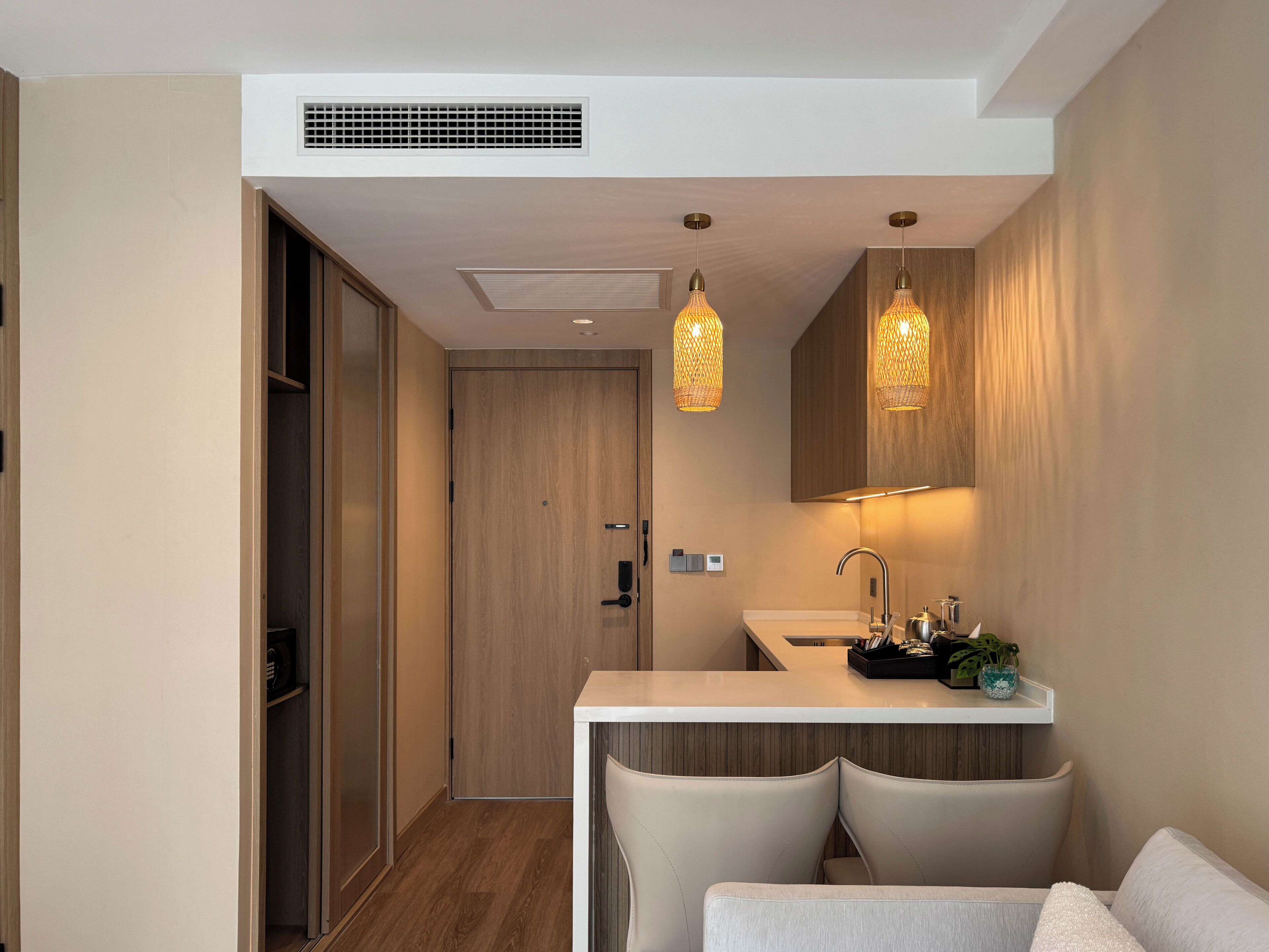 A modern bathroom with a wooden door, a sink, a mirror, and two pendant lights.