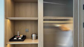Un interior moderno con estanterías de madera, un contenedor metálico y un separador de vidrio texturizado.