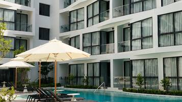 Un hôtel moderne doté d’une piscine, de nombreux balcons et d’un espace extérieur aménagé pour s’asseoir.