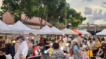 A crowded outdoor market with white tents and people browsing stalls.