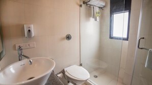 A bathroom with a sink, toilet, and glass-enclosed shower. - Hotel Diamond Tree (New Delhi)