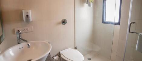 Une salle de bain équipée d’un lavabo, de toilettes et d’une douche à parois de verre.