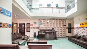 A hotel lobby with a reception desk, seating area, and a glass railing overlooking the lobby. - Hotel Diamond Tree (New Delhi)