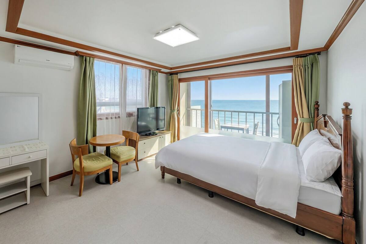 Una habitación de hotel con una cama, televisión, escritorio y una silla.