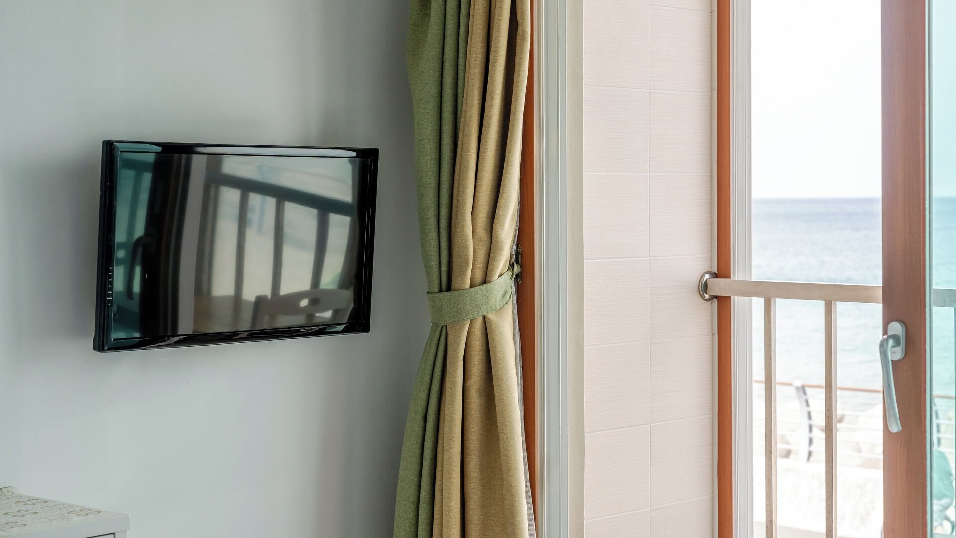 A bathroom with a mirror, a towel rack with a towel, and a view of the sea through a window.