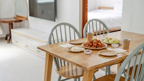 A dining table with plates of food, chopsticks, and a cup, set in a room with a bed and a TV. - Sokcho SBS Pension (Sokcho)