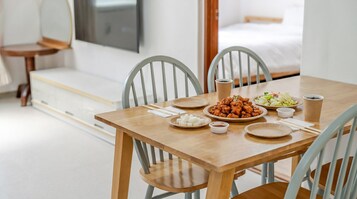 Una mesa de comedor con platos de comida, palillos y una taza, en una habitación con una cama y un televisor.