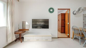 A room with a bed, a mirror, a wall-mounted clock, a door leading to another room, and a wall-mounted fan. - Sokcho SBS Pension (Sokcho)