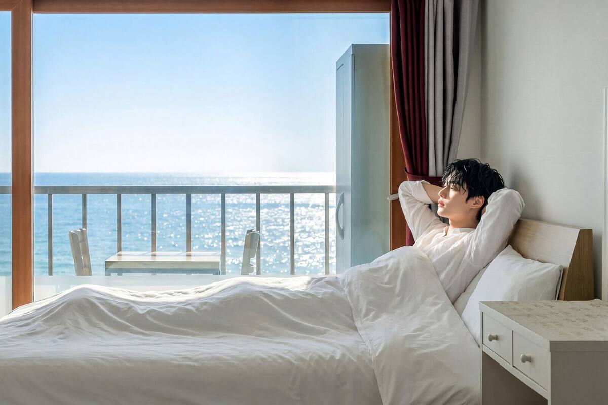 Una habitación de hotel con una cama, una mesita de noche, una silla y vista al mar.