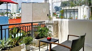 Un balcon avec une chaise, une table et des plantes en pot.