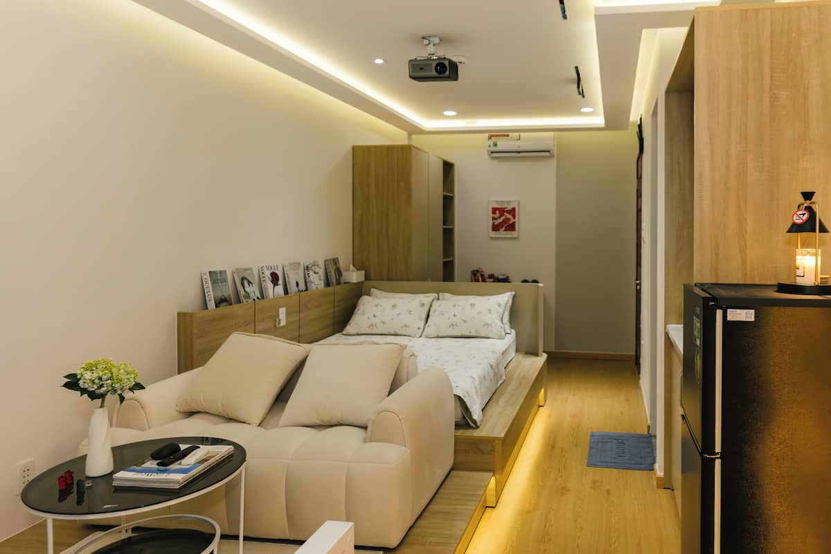 A modern hotel room with a bed, sofa, and a small table with a vase of flowers.