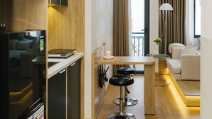 Une cuisine moderne dotée d’appareils électroménagers intégrés, un coin repas avec un tabouret de bar et un espace de vie comprenant un canapé et une lampe.