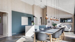 A modern kitchen with a central island, dark chairs, and pendant lights.