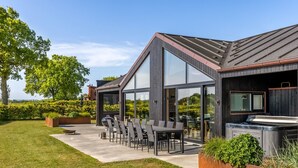 A modern house with a patio, outdoor seating, and a barbecue area.