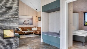 A modern interior with a brick accent wall, a seating area with a blue cabinet, and a bed with a view.