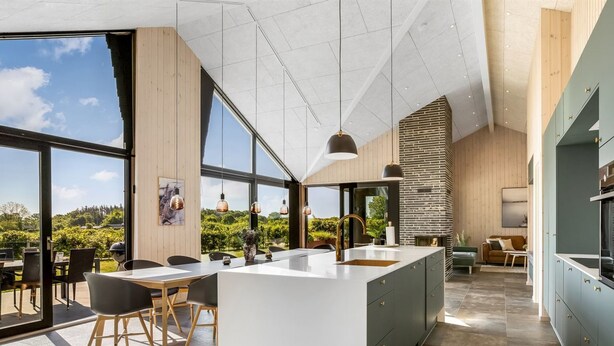 A modern kitchen with a large island, a dining area with chairs, and a view of the outdoors.