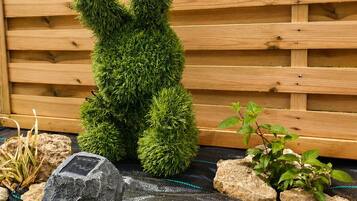 A wooden fence, a rock garden with plants, and a solar-powered device.