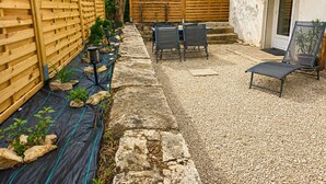 Une terrasse avec une table et des chaises, une clôture en bois et une plante en pot.