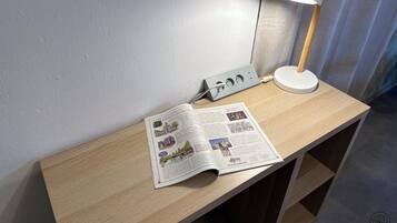 A wooden desk with a lamp, a power strip, and an open magazine.