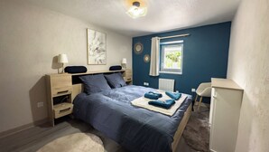 Une chambre à coucher avec un lit, des tables de chevet, un bureau et une fenêtre.