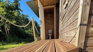 A wooden deck with a doormat featuring a circular design and the word "HOME". - A cottage in an orchard (Conteville)