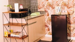 A compact kitchen with a microwave, a small refrigerator, and a wooden shelf unit. - Designer Inspired Cozy Abode in the Heart of Cebu City (Cebu City)