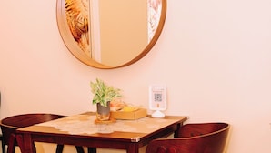 A dining area with a wooden table, four chairs, a round mirror, a small potted plant, and a QR code on the wall. - Designer Inspired Cozy Abode in the Heart of Cebu City (Cebu City)