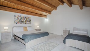 A bedroom with two beds, wooden ceiling beams, a colorful abstract painting, and bedside lamps. - Lo Stagnone Apartments (Marsala)