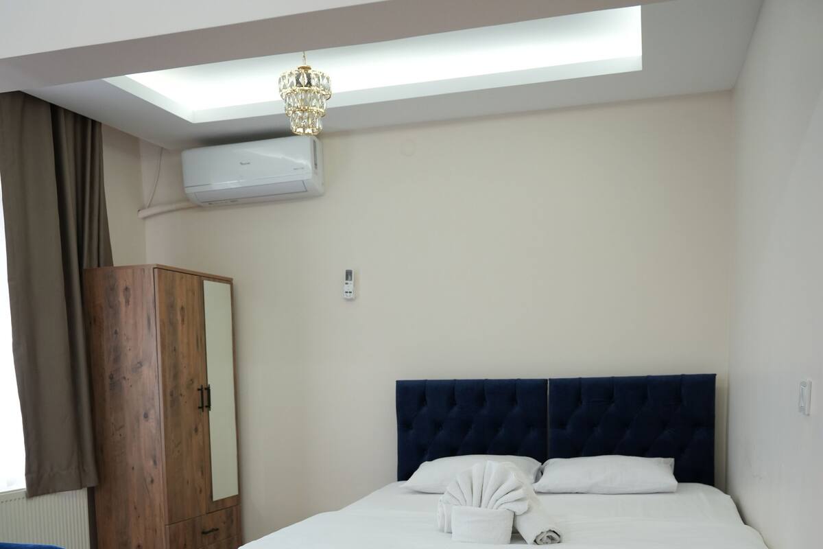 A bedroom with a bed, a wardrobe, a desk, and a ceiling light.